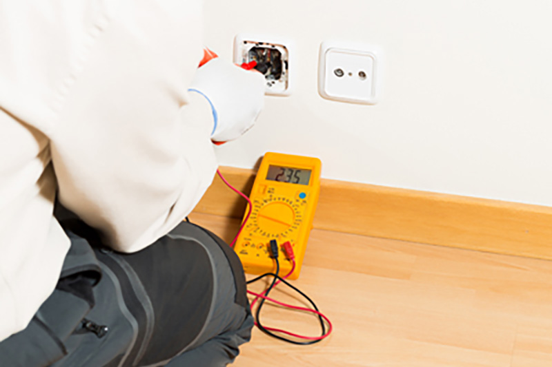 How to Hire an Electrician. Electrician working on outlet.